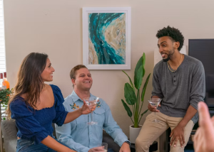 Two men sitting and talking with drinks in a living room